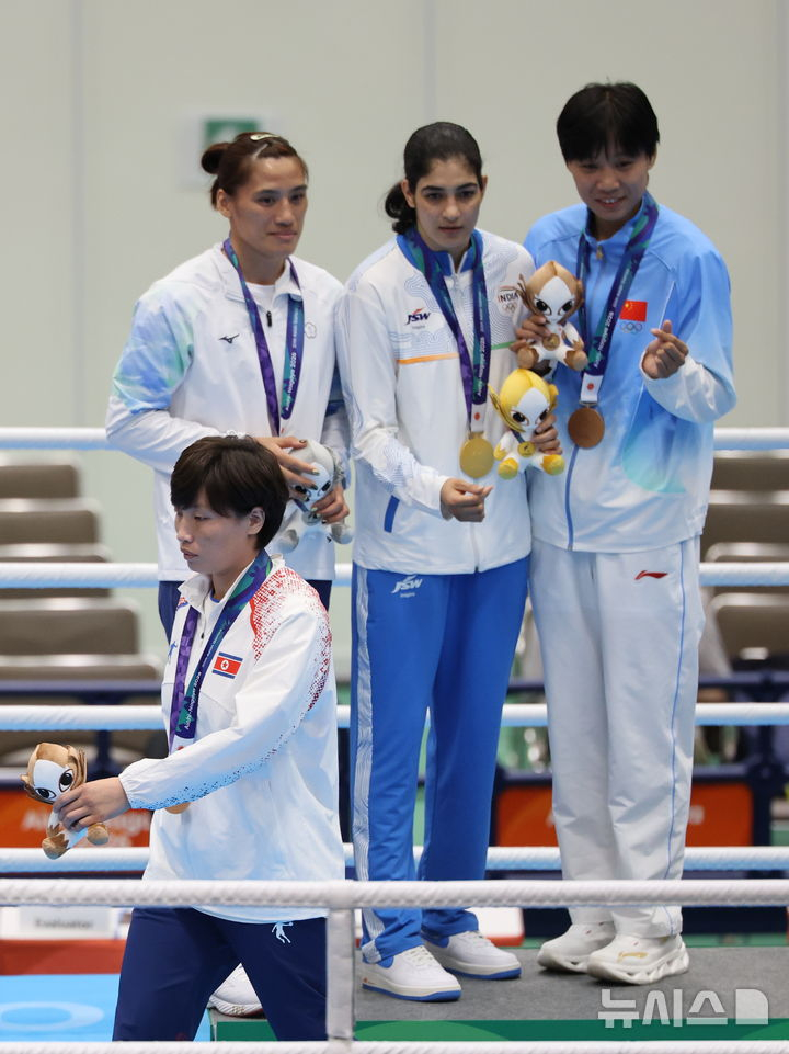 2026 아이치·나고야 아시안게임 복싱 여자 65kg 시상식에서 동메달을 획득한 북한 황효순이 다른 메달 수상자들과의 손하트 기념촬영을 거부하고 자리를 이동하고 있다. /사진=뉴시스