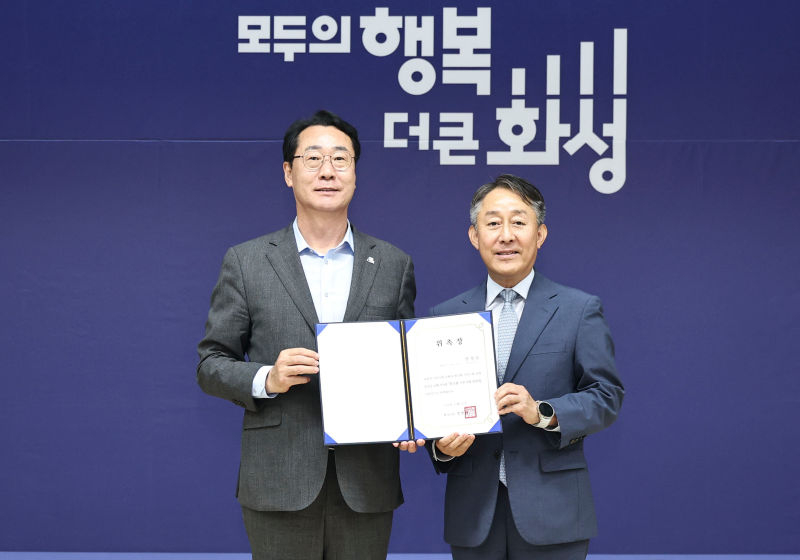 정명근 화성특례시장(왼쪽)이 양성일 화성형 기본사회위원회 위원장(오른쪽)에게 위촉장을 수여한 뒤 기념촬영을 하고 있다./사진제공=화성시