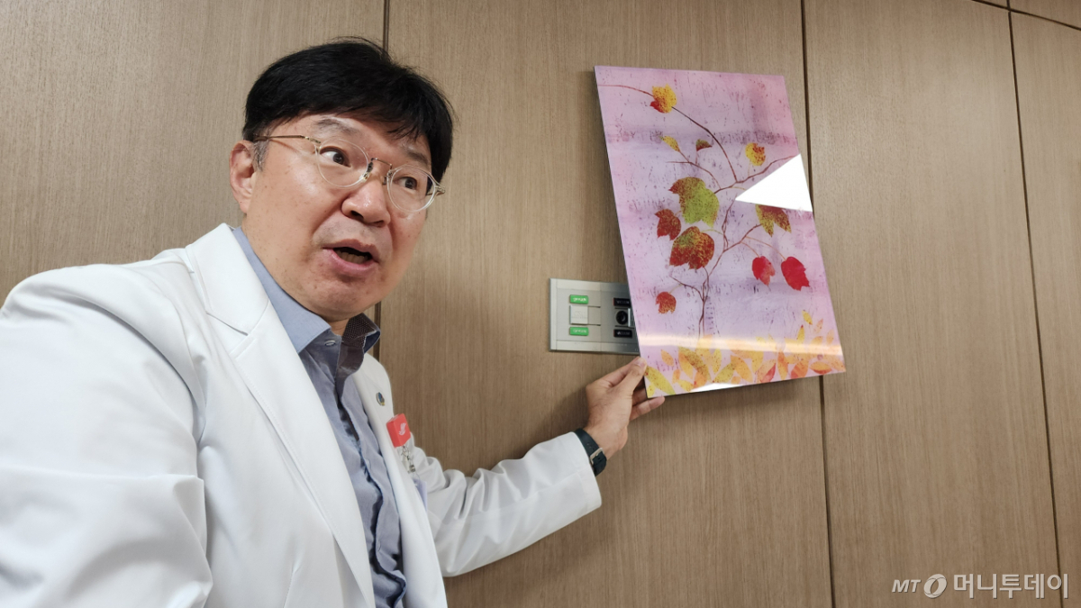 한림대춘천성심병원 이태헌 응급의학과 교수(기획실장)가 권역응급의료센터 1층 내 걸린 액자에 감춰진 벽면을 기자들에게 공개하고 있다. 액자들이 걸린 벽면엔 대형사고로 인한 대규모 응급환자 수용을 대비해 산소호흡기와 석션(흡입기)을 꽂을 수 있는 전용 콘센트가 설치돼 있다. /춘천(강원도)=정심교 기자