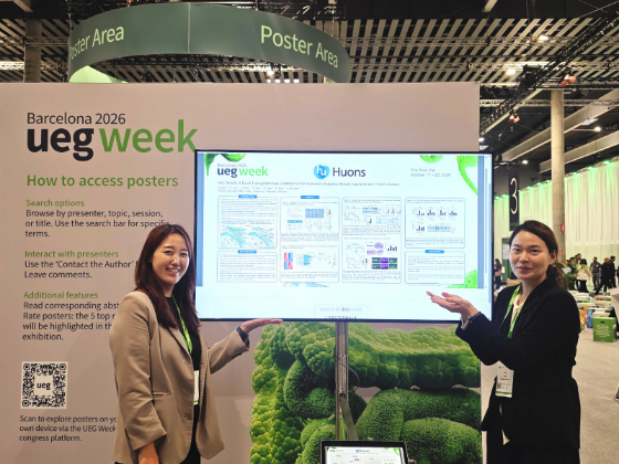 휴온스 관계자들이 스페인 바르셀로나에서 열린 'UEG Week 2026'에서 HUC1A-626 발표 포스터를 두고 설명하고 있다. /사진=휴온스
