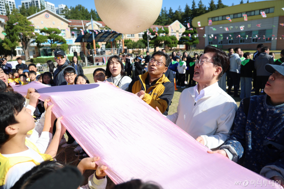 [익산=뉴시스] 김진아 기자 = 이재명 대통령이 22일 전북 익산 왕궁초등학교에서 열린 가을 행복학교 체육한마당에서 학생들과 '짐볼 이동하기'를 하고 있다. 2026.10.22. bluesoda@newsis.com /사진=김진아