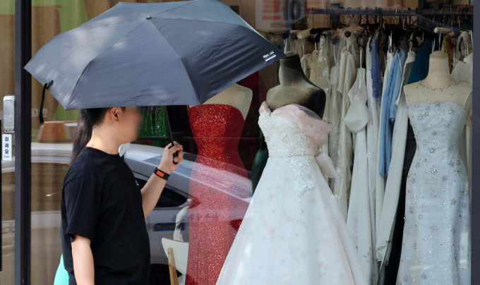A view of young people looking at wedding dresses on display in the wedding town area of Ahyeon-dong, Seodaemun-gu, Seoul. The photo is not directly related to the article. /Photo=News1.