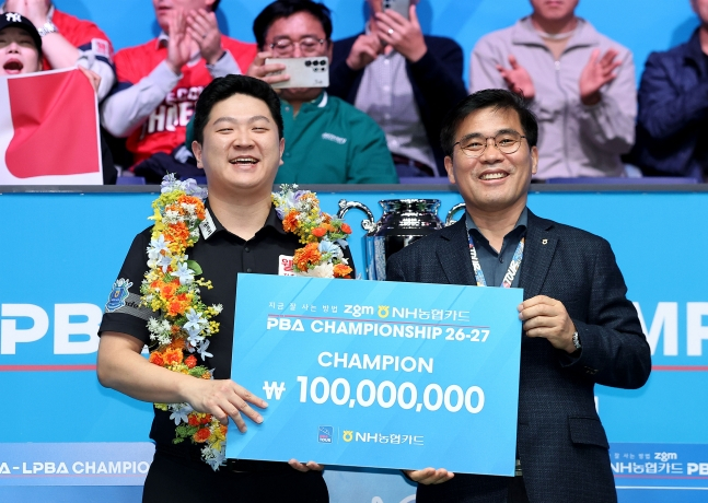 조건휘(왼쪽)가 27일 경기도 고양시 '고양 킨텍스 PBA 스타디움'에서 열린 프로당구 2026-2027시즌 5차 투어 '지금 잘 사는 방법 zgm NH농협카드 PBA-LPBA 챔피언십' PBA 결승전에서 승리 후 우승을 차지한 뒤 이정환 NH농협카드 사장으로부터 상금 1억원을 건네 받고 활짝 웃으며 기념촬영을 하고 있다. /사진=PBA 투어 제공