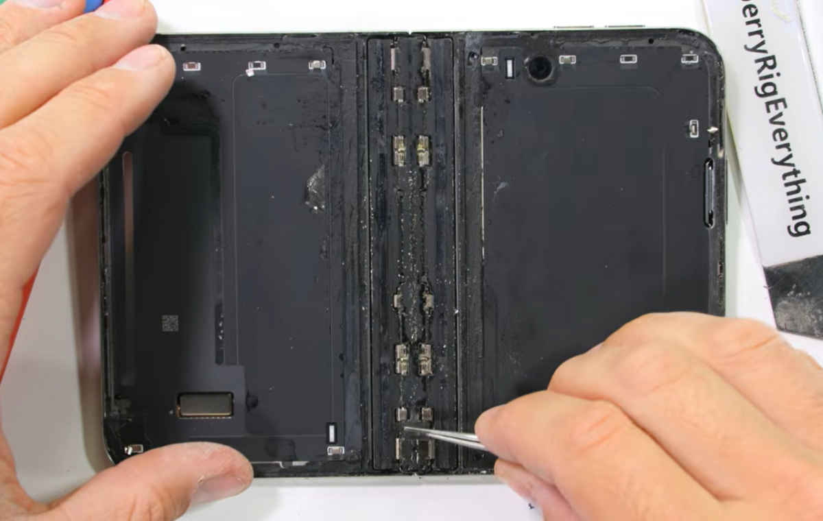The interior of the iPhone Duo showing sand and dust stuck in various places after durability testing / Screenshot from JerryRigEverything YouTube channel